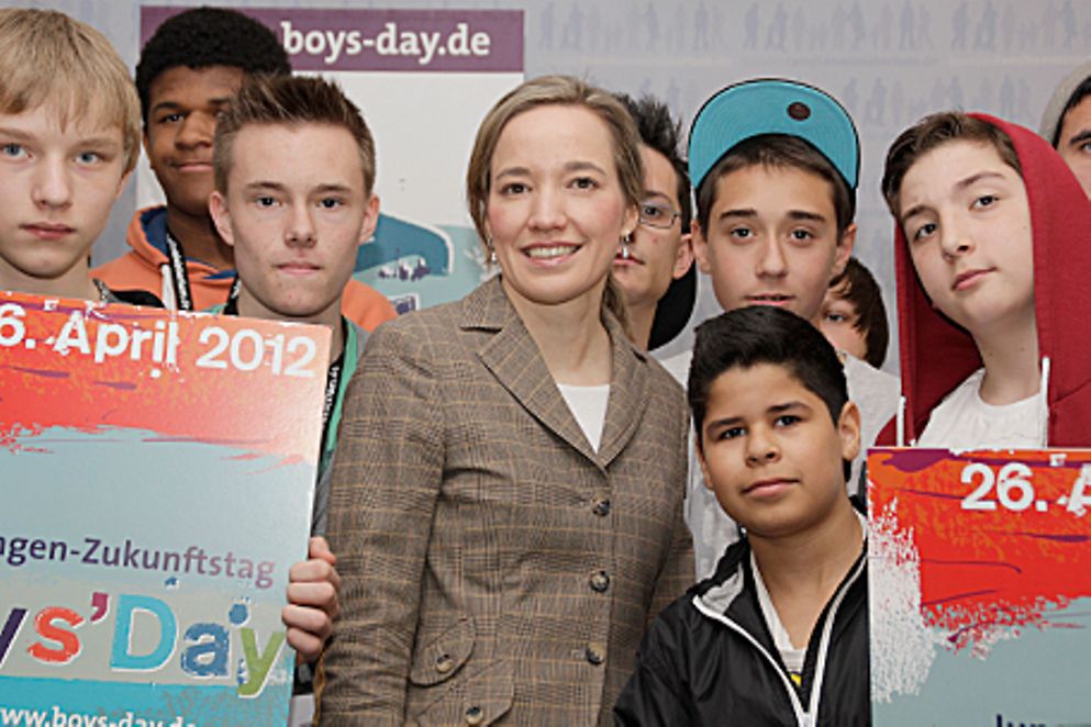 Kristina Schröder und Jungen stehen vor einer Plakatwand des Boys' Day 2012. Bildquelle: BMFSFJ