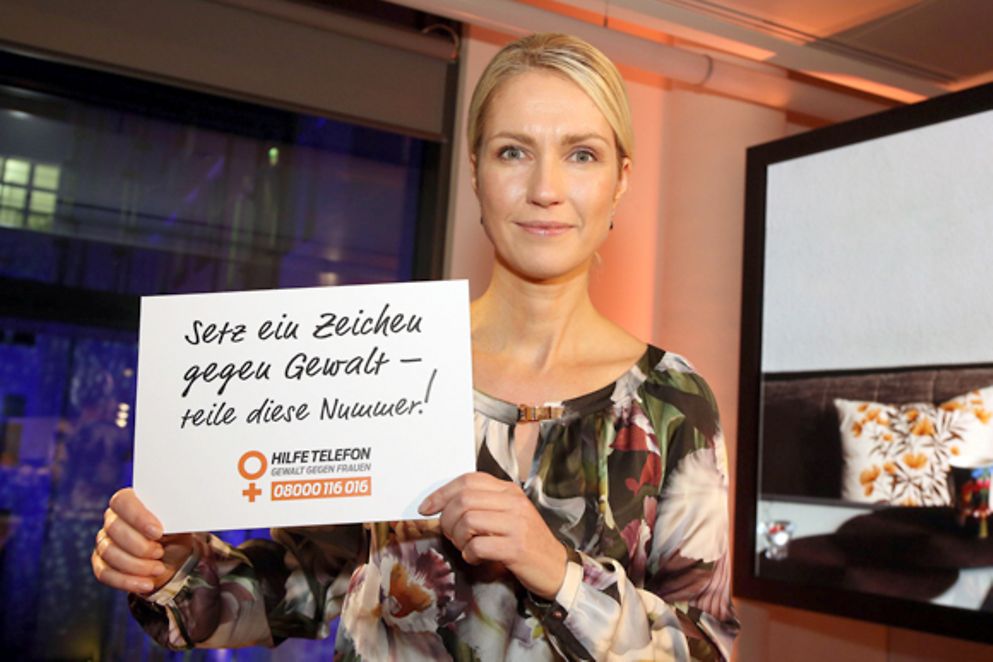 Manuela Schwesig hät ein Schild in der Hand mit der Aufschrift "Setz ein Zeichen gegen GEwalt - teile diese Nummer!"