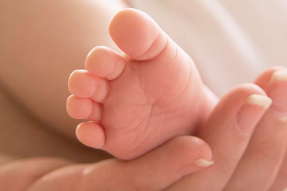 Die Hand eines Erwachsenen stützt den Fuß eines Babys, Bildnachweis: BMFSFJ