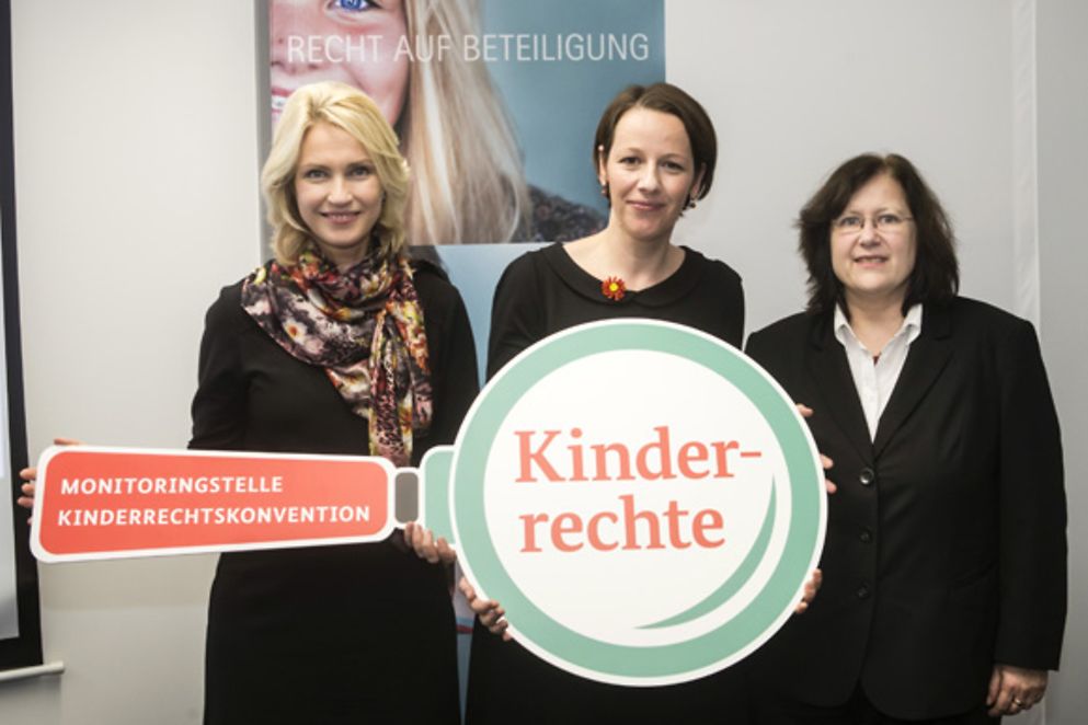Manuela Schwesig, Claudia Kittel und Beate Rudolf halten eine Lupe mit der Aufschrift "Kinderrechte"