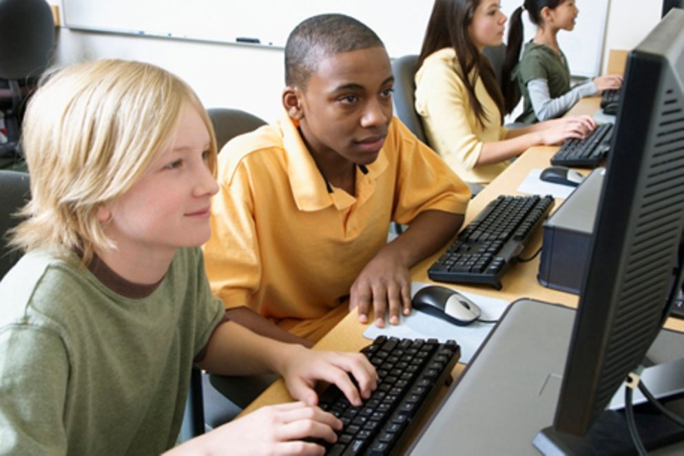 Zwei Jungen und zwei Mädchen sitzen an vier PCs und surfen im Internet.