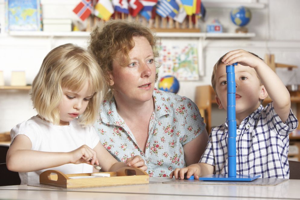Eine Erzieherin spielt mit zwei Kindern