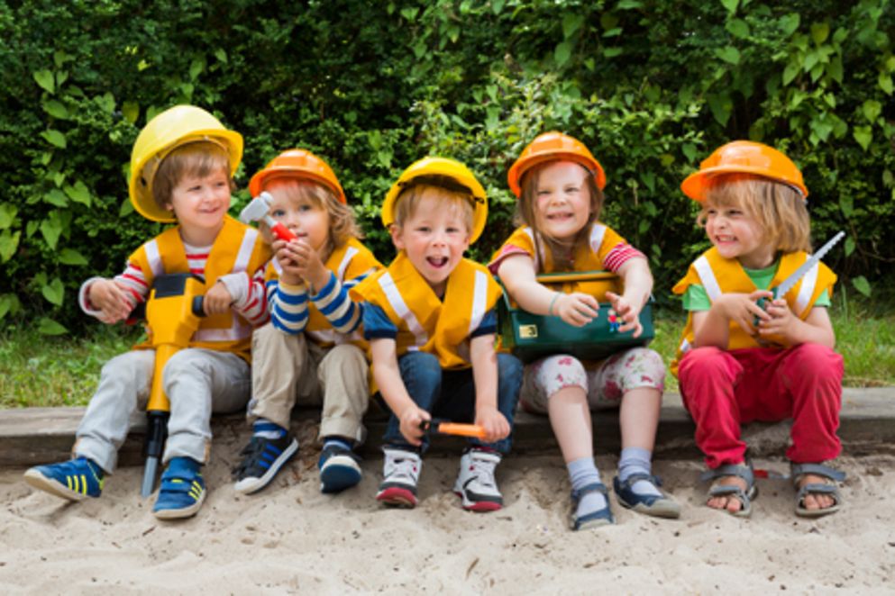 Kinder sitzen in einem Sandkasten, Bildnachweis: BMFSFJ