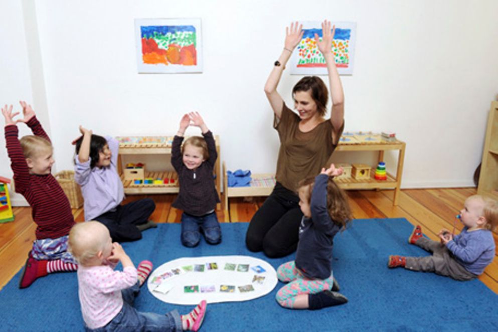 Eine Betreuuerin spielt mit Kindern und Kleinkindern in einer Kita. Bildquelle: M. Gronau / BMFSFJ
