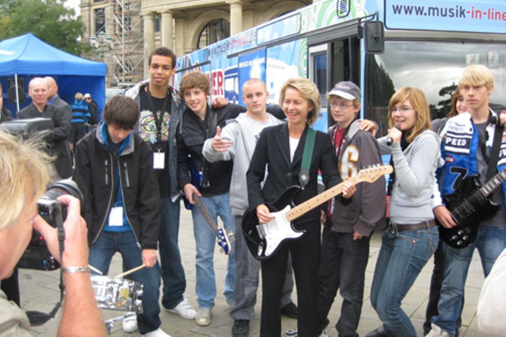 Ursula von der Leyen und Jugendliche musizieren vor dem Soundbus.