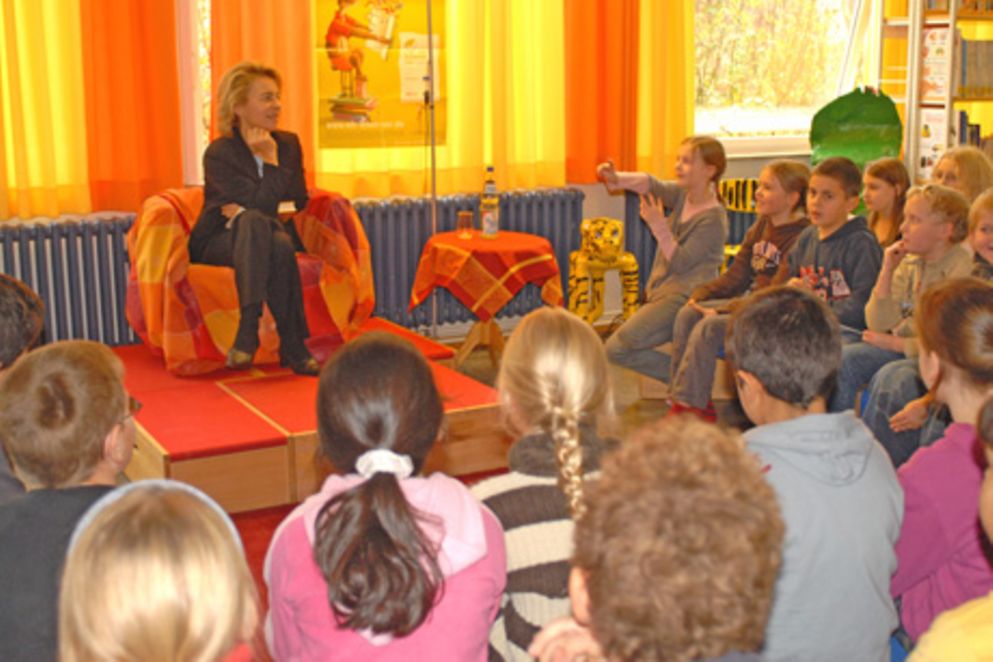 Ursula von der Leyen liest Schülerinnen und Schüler aus einem Astrid-Lindgren-Buch vor.