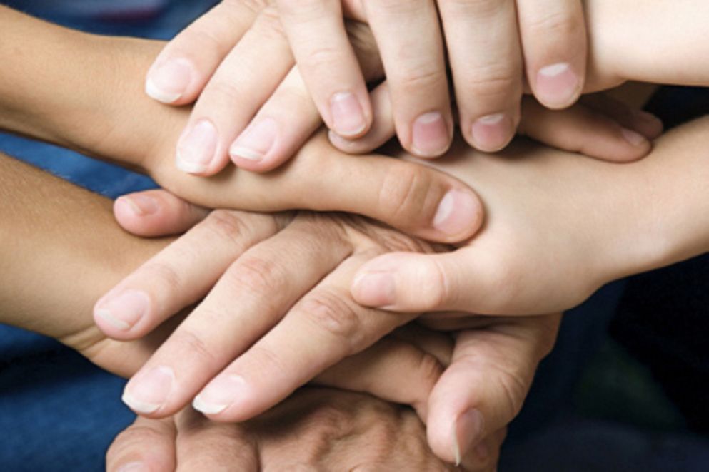 Mehrere Hände junger und älterer Menschen liegen übereinander.