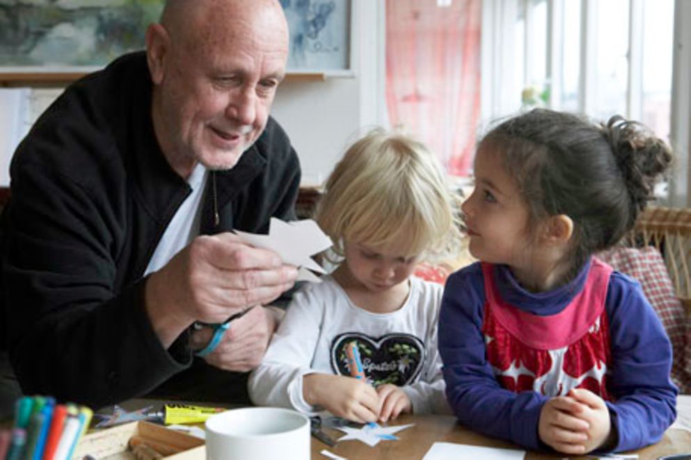 Ein älterer Mann bastelt mit zwei kleinen Kindern.