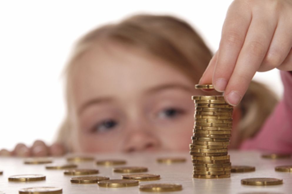 Ein Kind stapelt Münzen auf einem Tisch