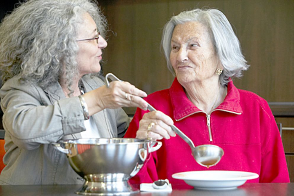 Ältere Frau mit ihrer Betreuerin beim Essen