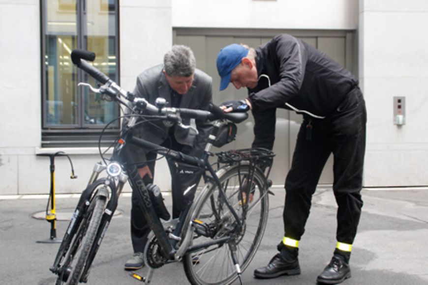 Ein Mitarbeiter und ein Fahrradspezialist sind über ein Fahrrad gebeugt, Bildnachweis: BMFSFJ