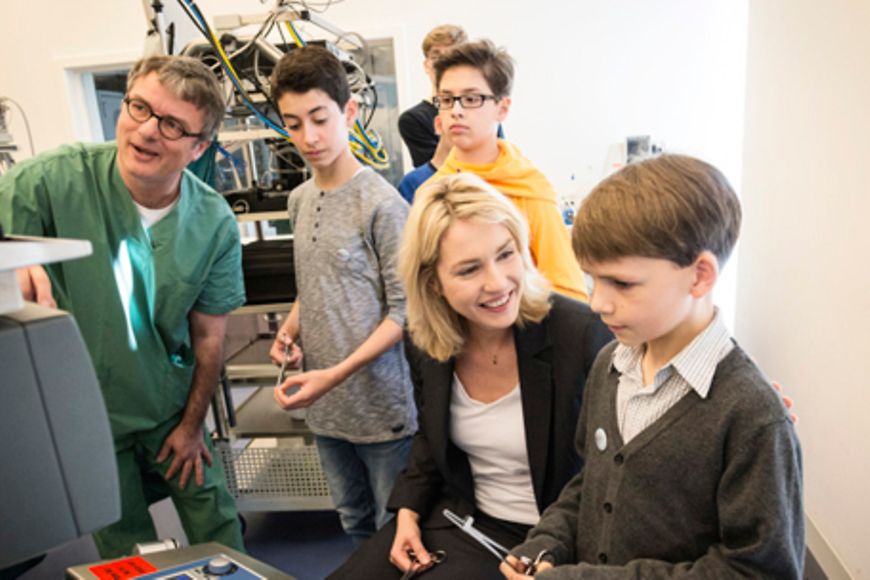 Manuela Schwesig mit Teilnehmern des Boys'Day sowie einem Arzt im Simulations-Operationssaal. Bildnachweis: Holger Talinski