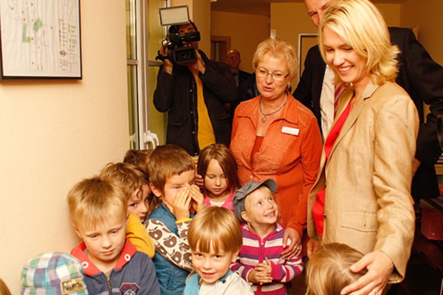 Manuela Schwesig steht gemeinsam mit den Kita-Kindern und einer Erzieherin auf dem Flur der Kita