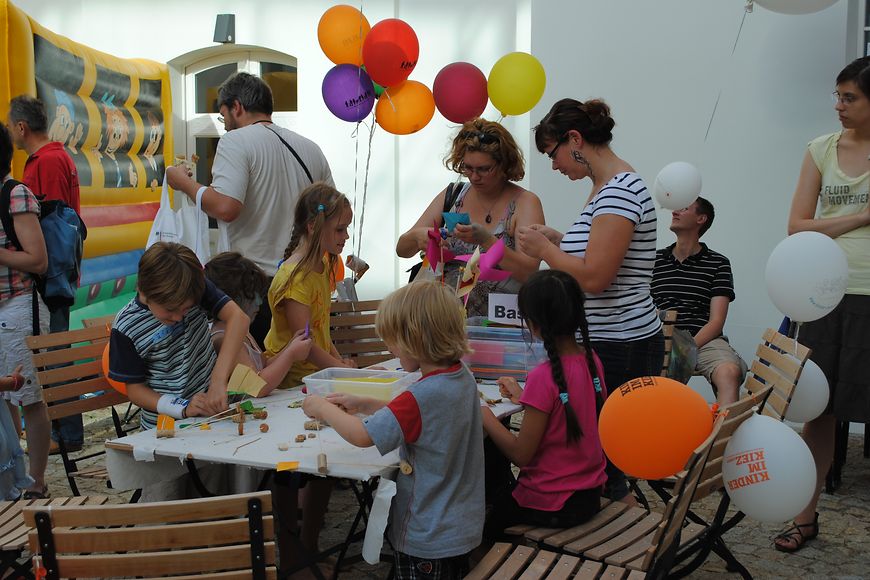 Kinder und Erwachsene basteln an einem Tisch. Bild: BMFSFJ